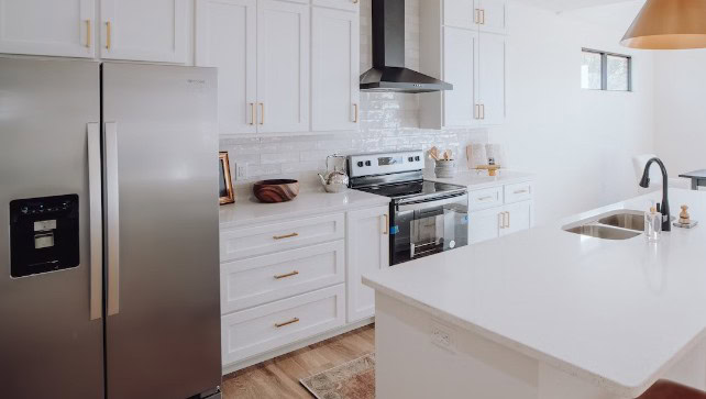 A kitchen with white cabinets and a stainless steel refrigerator.