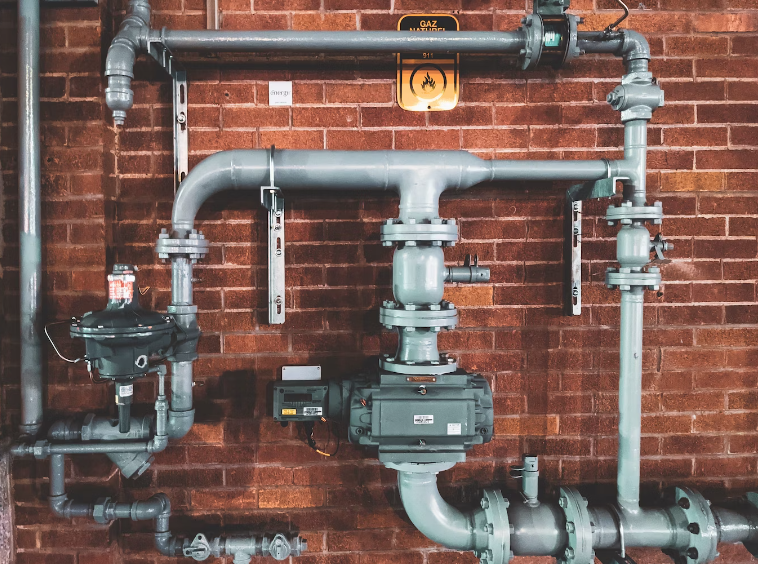 A plumbing system consisting of water pipes and valves on a brick wall.