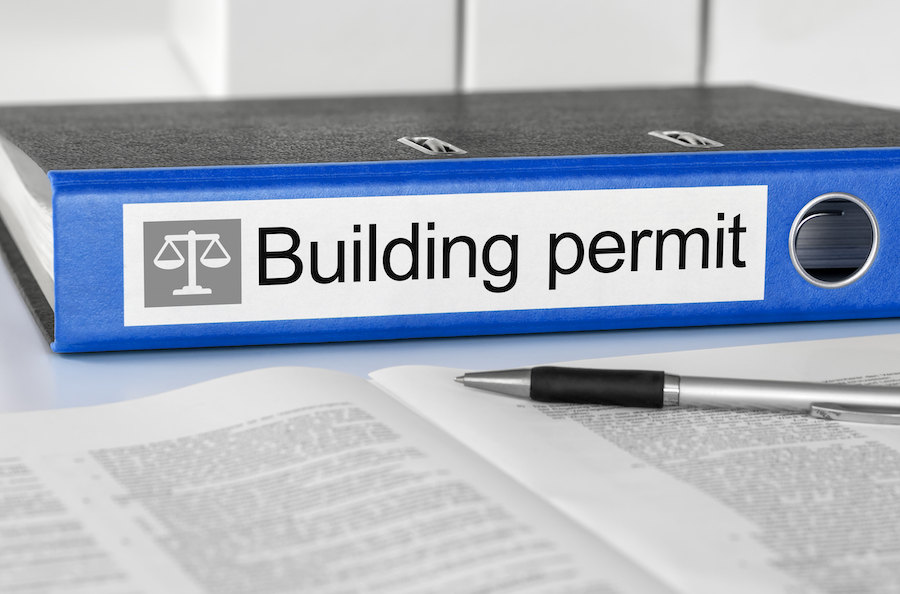 A blue binder displaying a building permit on top, complying with building regulation.