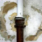 A white drain cleaning pipe is sitting on top of a wall.