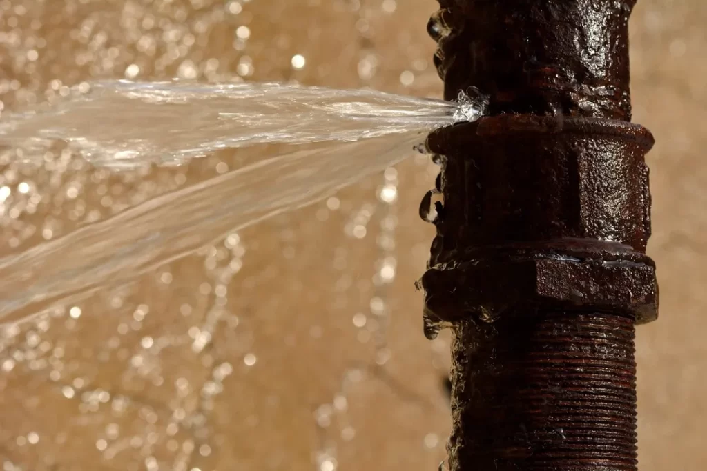 A water pipe with water coming out of it, indicating a possible drain problem or the need for drain cleaning.