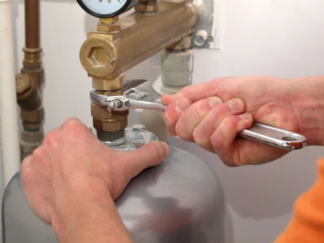 A plumber is working on a water heater to fix it.