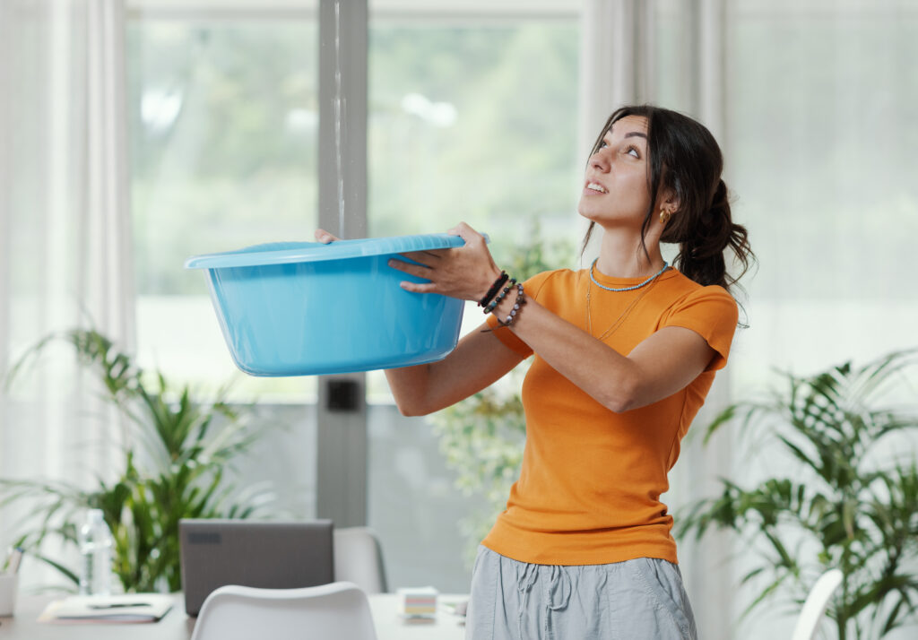 Woman collecting water leaking from the ceiling