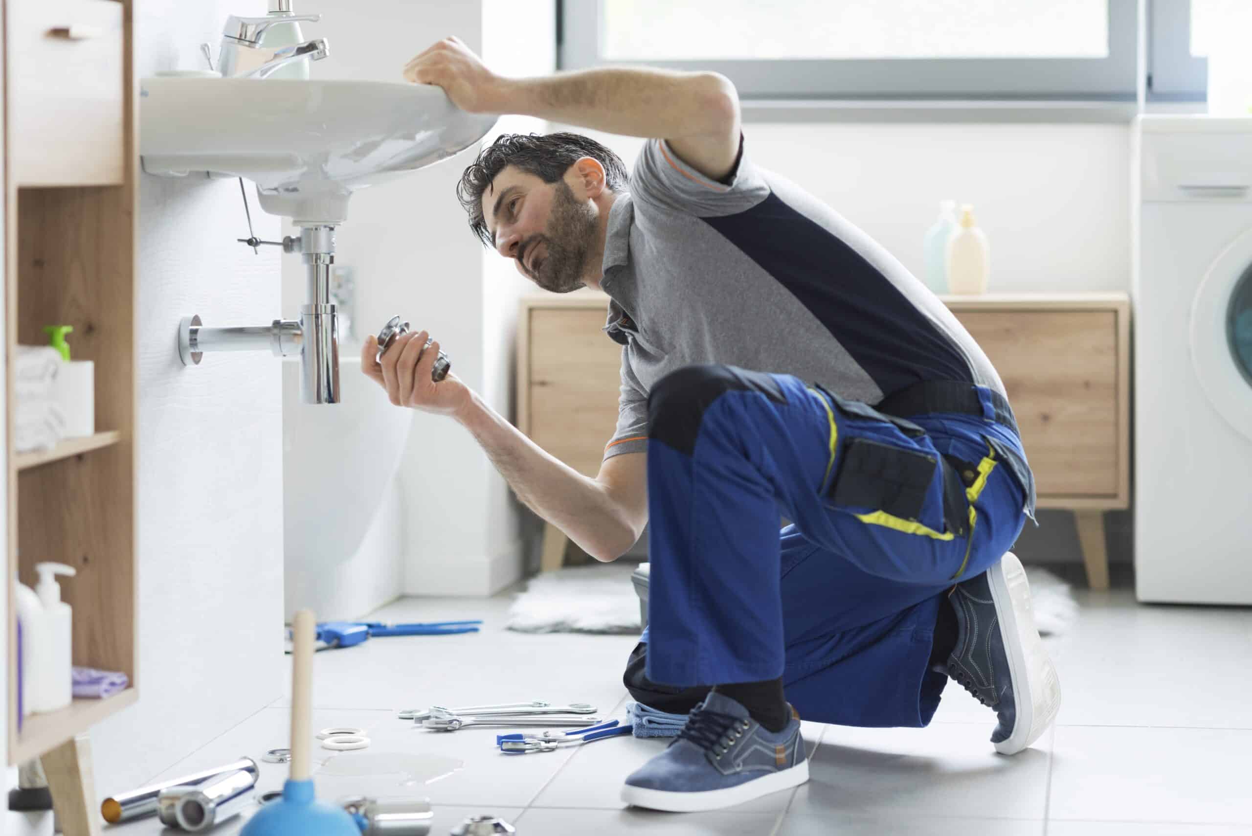 person installing sink drainage pipe